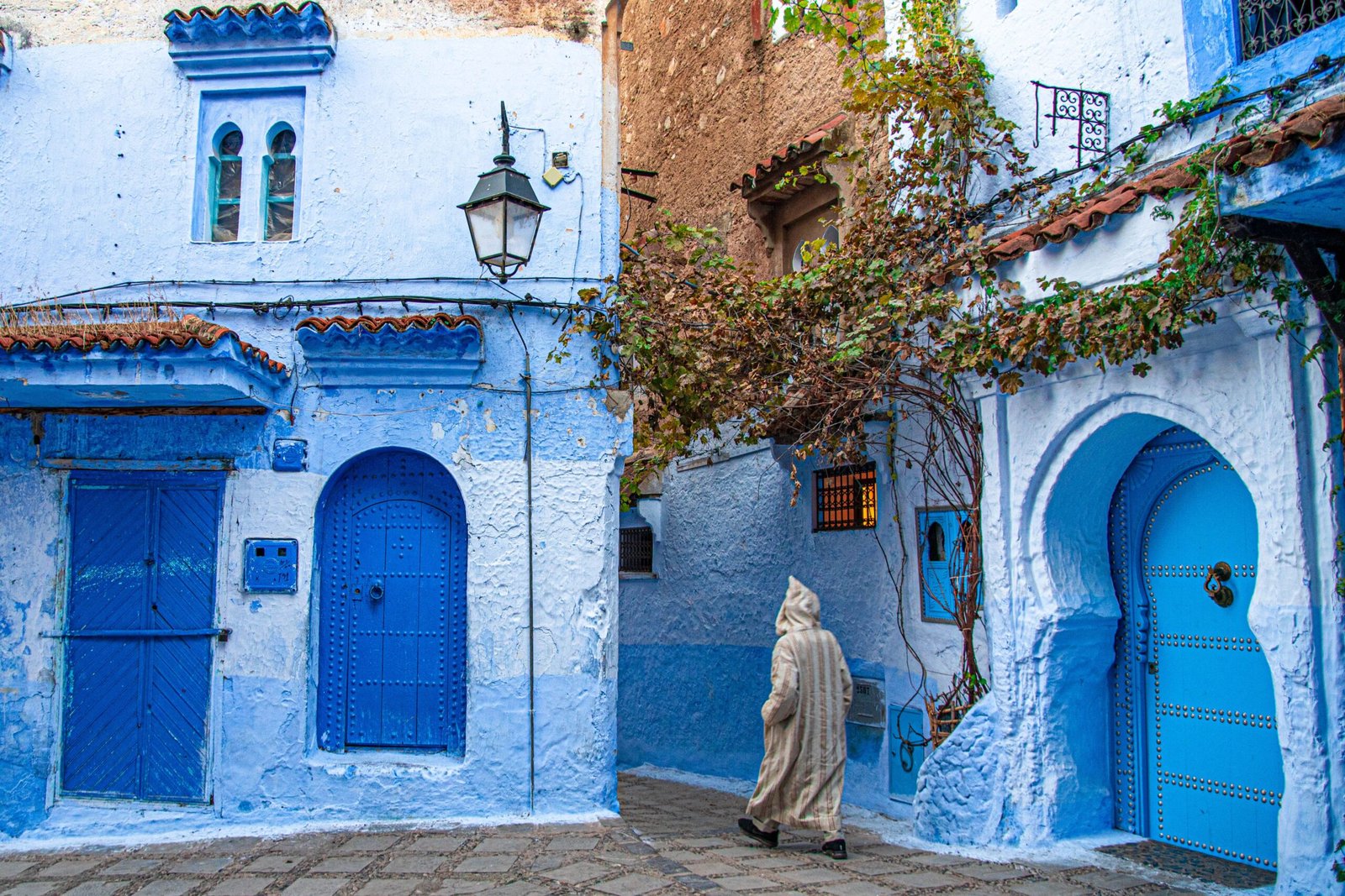 A vibrant street scene in Chefchaouen, Morocco, showcasing traditional blue-painted architecture.