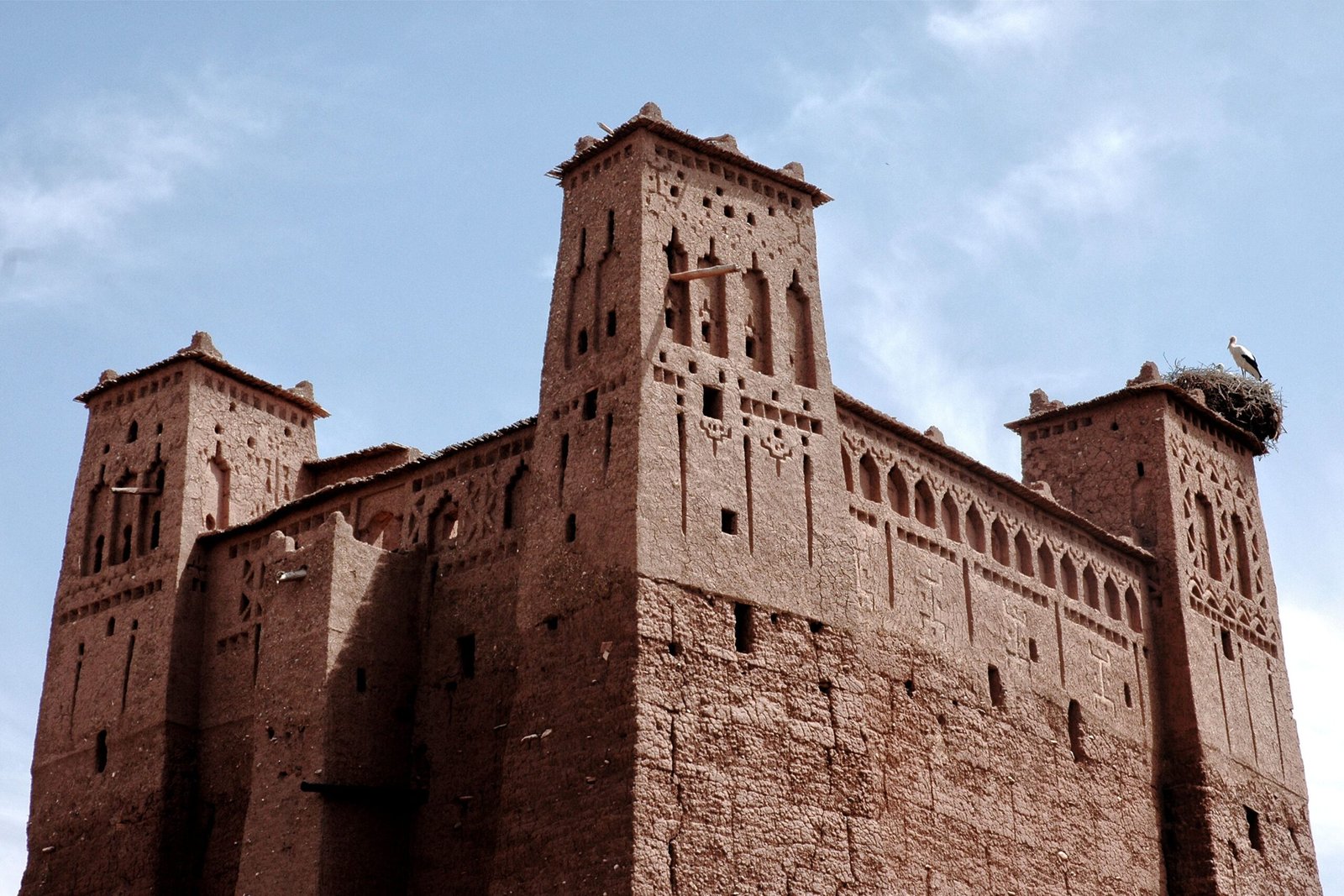 Captivating view of a traditional Kasbah in Ouarzazate, Morocco under a clear blue sky.