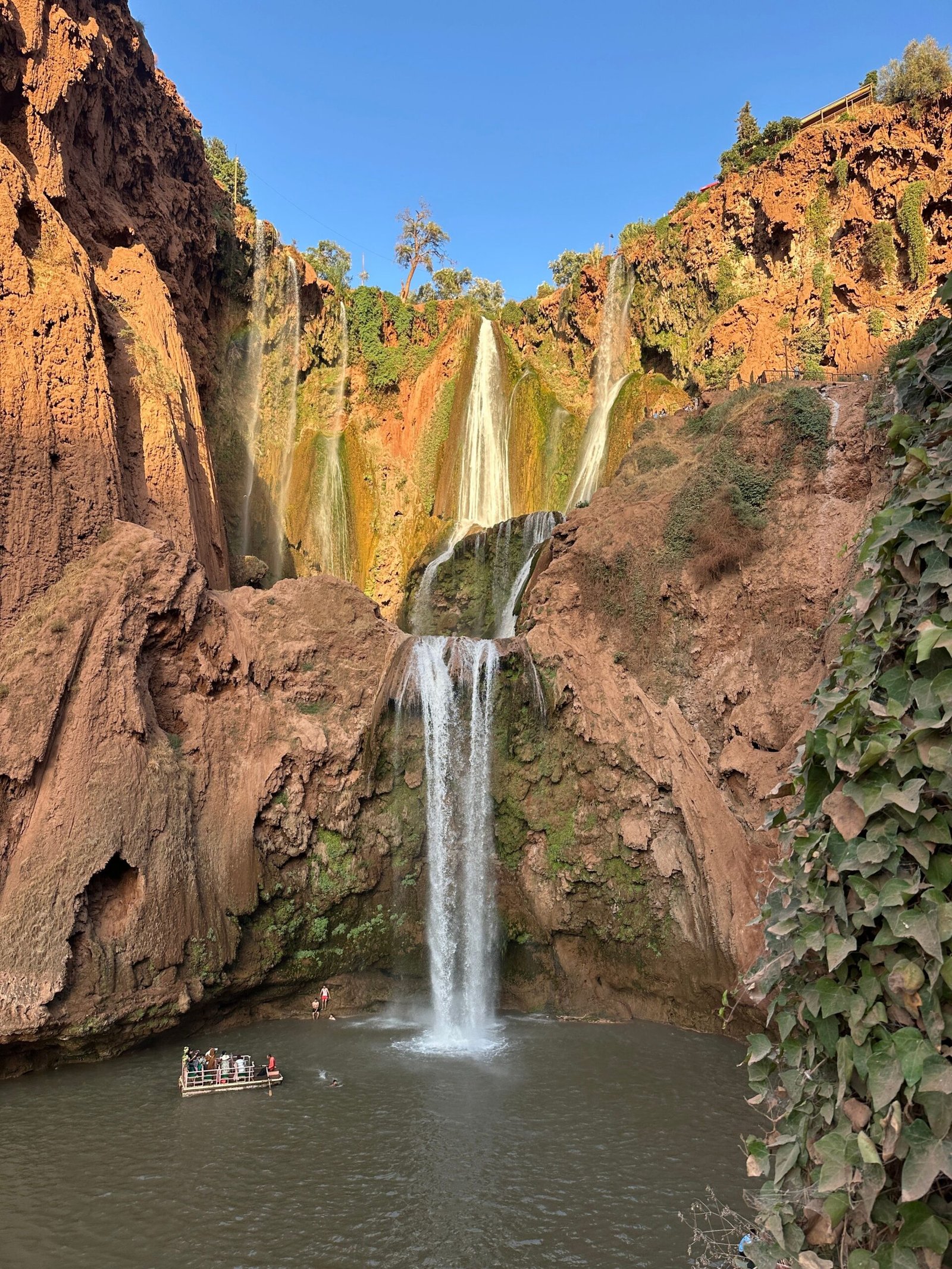 Stunning view of the Ouzoud Waterfalls in Morocco with visitors on a boat enjoying the natural beauty.