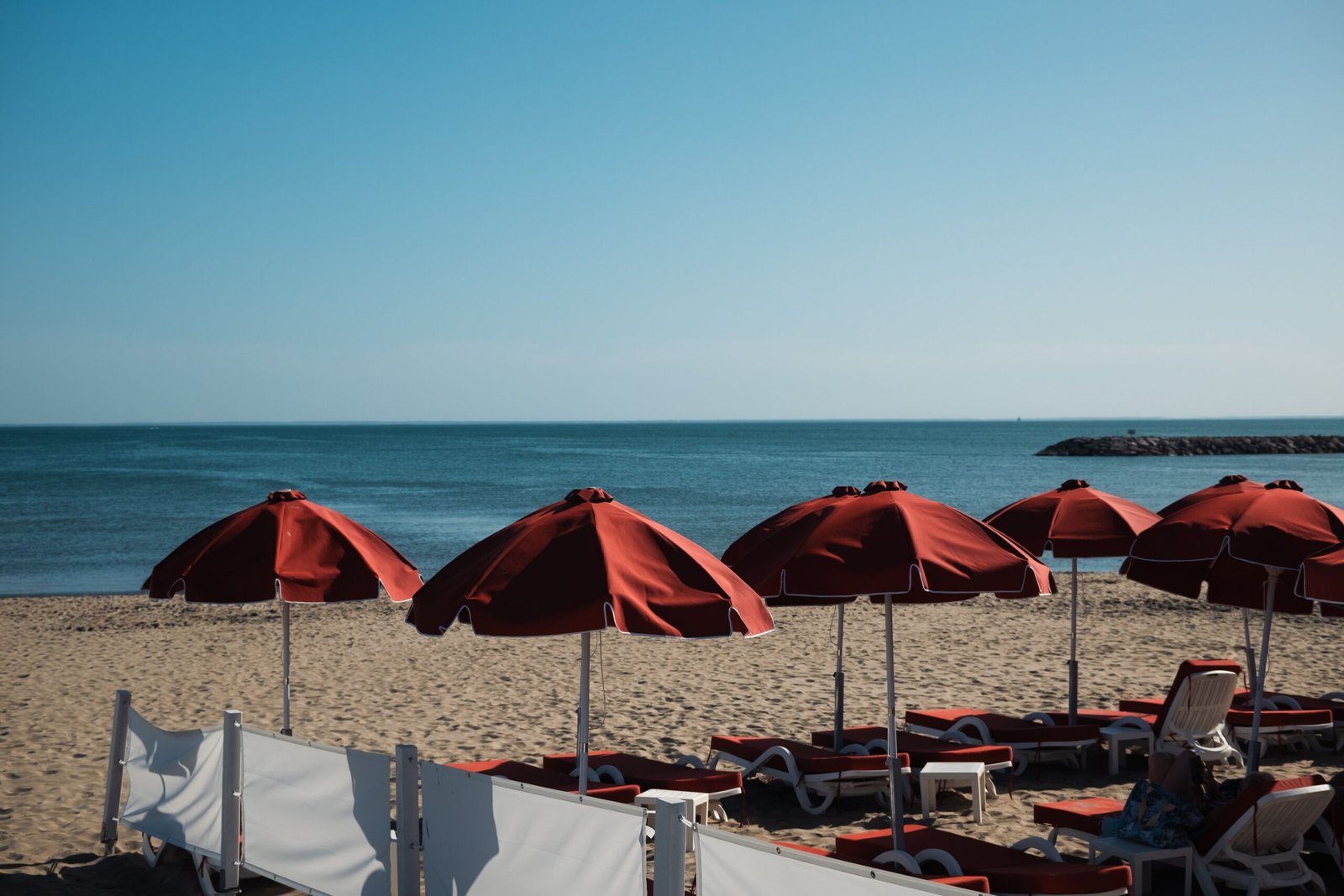 Scenic view of red parasols on La Grande-Motte beach, France, with the Mediterranean Sea.